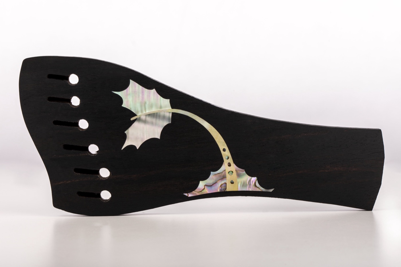 Mother-of-pearl flourish inlay on an acoustic guitar bridge